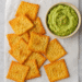 Crispy gouda cheese chips served with creamy avocado lime dip on parchment paper